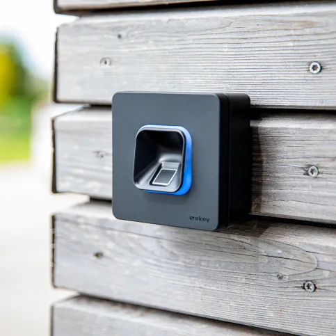 Den ekey xLine Fingerprint gibt es sowohl als Unter- als auch (wie hier abgebildet) als Aufputzvariante. Moderne Fingerabdruckleser-Installation an einer Holzfassade