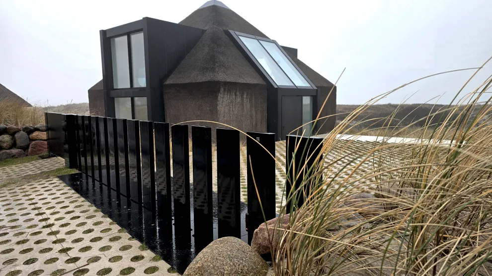 Private Toranlage auf Sylt mit versenkbaren Paneelen Futuristisches Wohnhaus mit schrägen Dächern, Holzverkleidung und großen Fensterflächen
