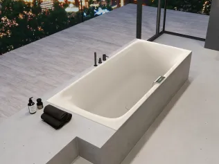 Freistehende Badewanne aus Acryl mit Betonablage und minimalistischer Armatur