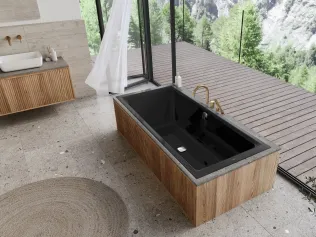 Freistehende Badewanne aus schwarzem Material mit Holzverkleidung in einem lichtdurchfluteten Badezimmer