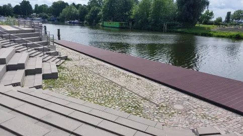 Terrassierte Uferpromenade mit Natursteinbelag und Holzsteg am Wasser