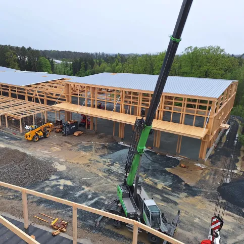 Holzrahmenbau mit großen Fensterfronten und Stahlträgern auf einer Baustelle