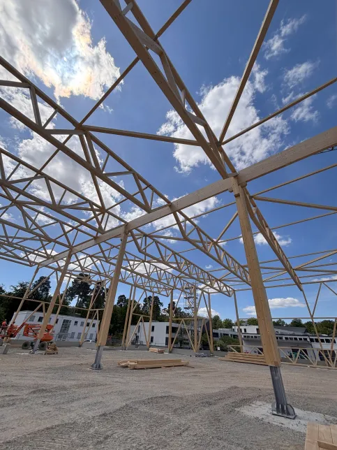 Holztragwerke von LIGNA® systems Holztragwerk mit sichtbarem Dachstuhl und Betonfundament auf einer Baustelle
