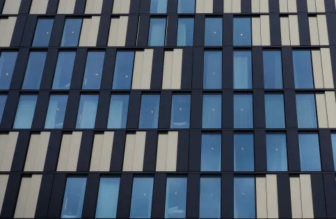Fassadenansicht eines Bürogebäudes mit vertikalen Aluminiumverkleidungen und großen Fensterflächen.