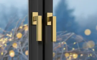 Türgriff aus gebürstetem Edelstahl mit goldenen Akzenten vor unscharfem Hintergrund