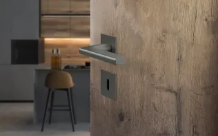 Detailaufnahme einer Holzinnentür mit modernem Türgriff und Sicht auf eine minimalistische Küche im Hintergrund