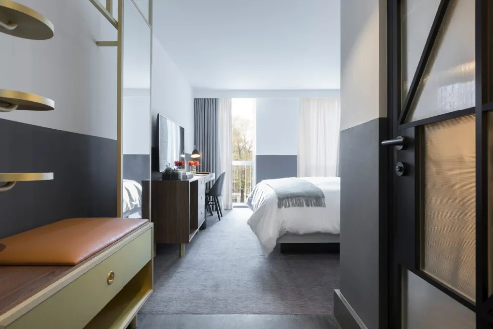Türbeschlag Rhodos ER28 im Kimpton De Witt Hotel in Amsterdam Hotelzimmer mit minimalistischer Einrichtung, großen Fenstern und modernen Möbeln aus Holz und Metall