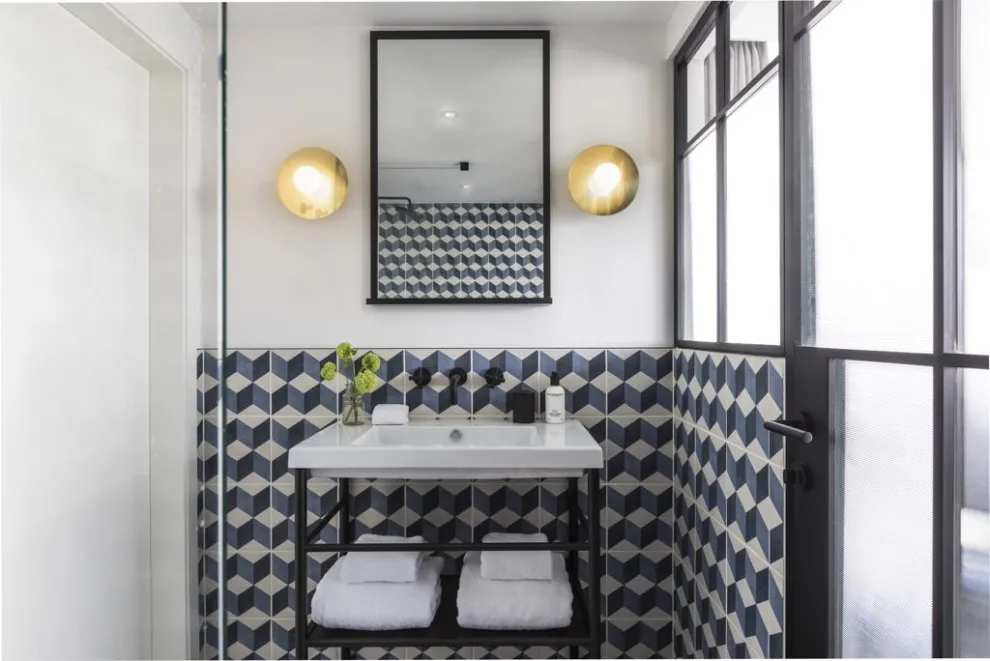 Black Edition Rhodos ER28 in Kosmos Schwarz | Luxeriöses Ambiente im Kimpton De Witt Hotel in Amsterdam Badezimmer mit geometrischen Fliesen, freistehendem Waschbecken und modernen Leuchten