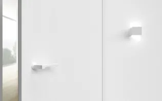 Minimalistische Innentür aus weißem Holz mit modernem Türgriff und integrierter Wandbeleuchtung