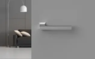 Türgriff aus gebürstetem Edelstahl an einer grauen Wand mit minimalistischer Einrichtung im Hintergrund